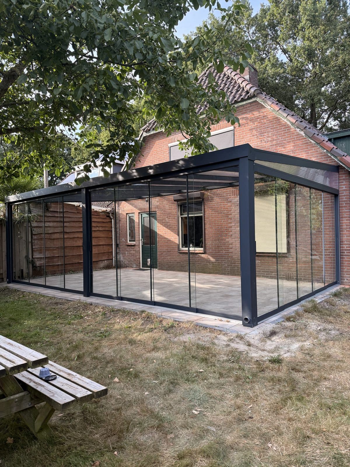Overkapping met glazen schuifwanden bij een jaren-30 woning, gezien vanuit de tuin