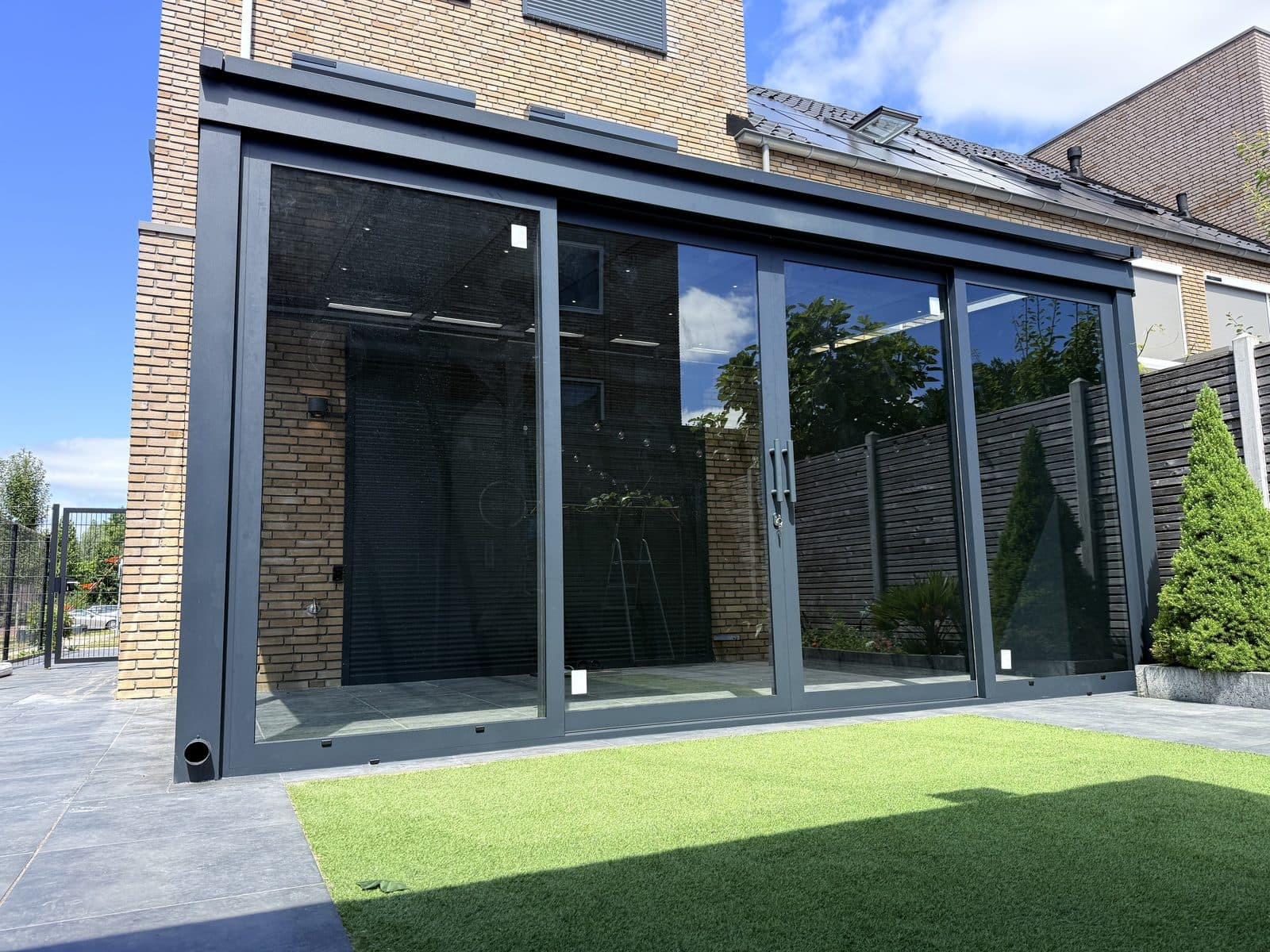 Opgeleverde overkapping met glazen schuifwanden en zonwering