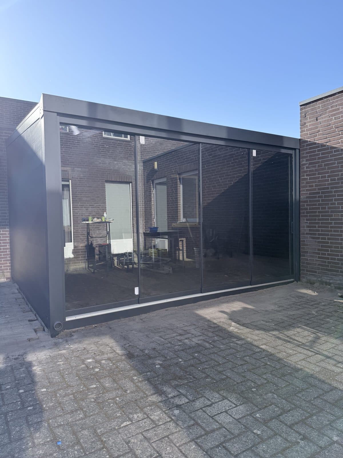Overkapping met glazen schuifwand op een bestraat terras