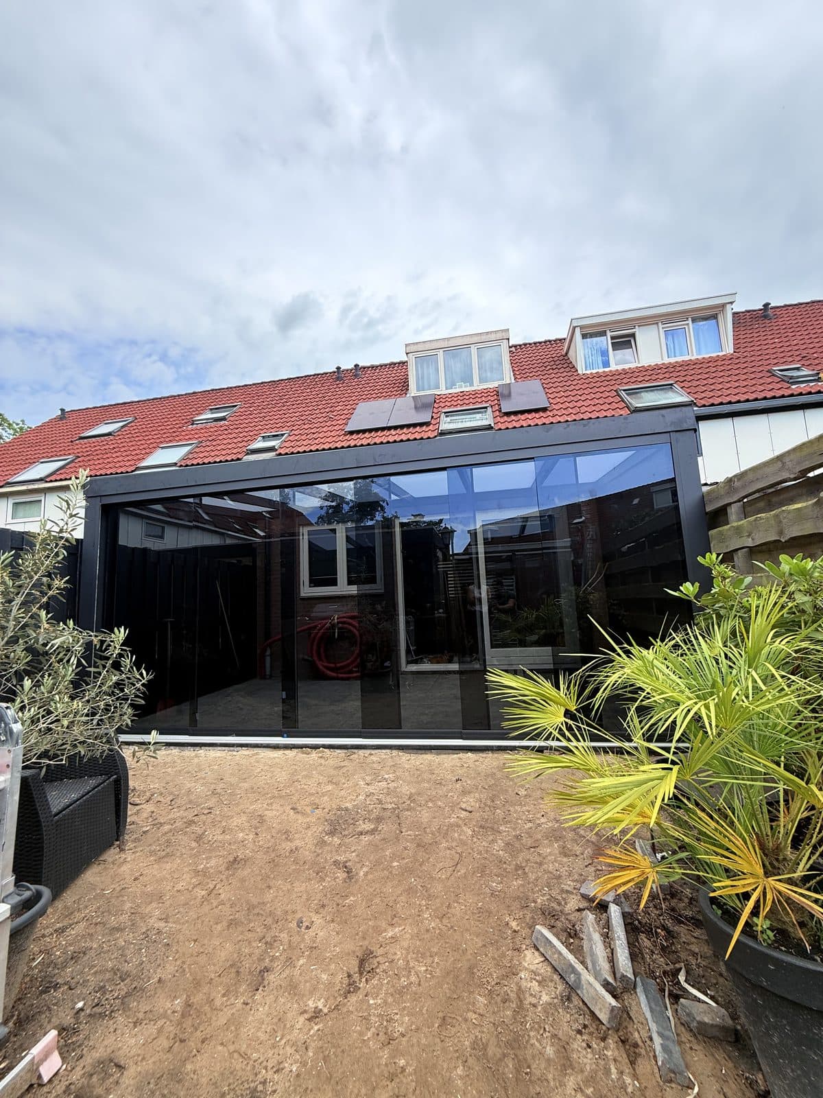 Overkapping met getinte glazen schuifwand aan de achtergevel