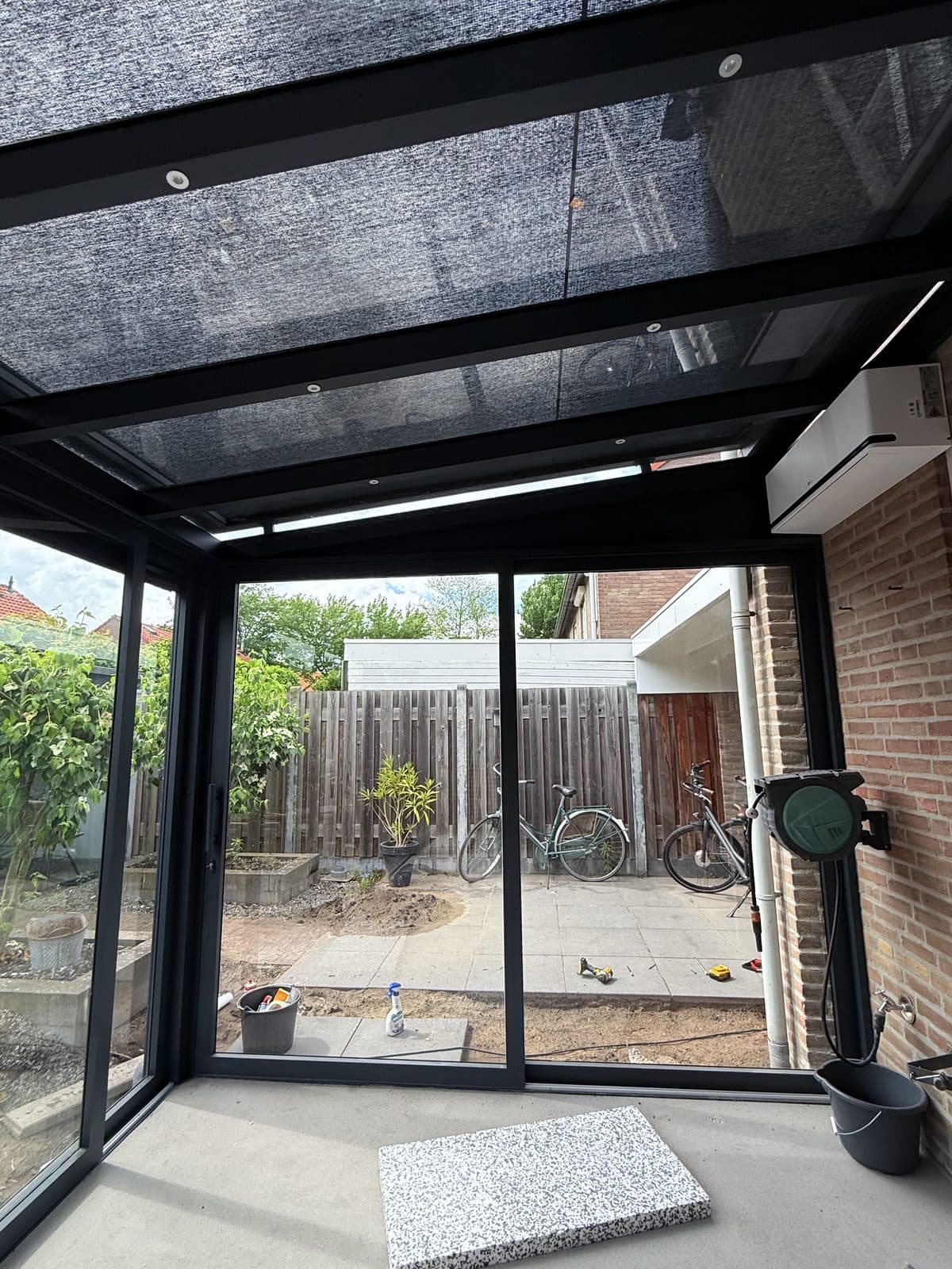 Zicht vanuit de overkapping op de tuin, met de schuifwand dicht