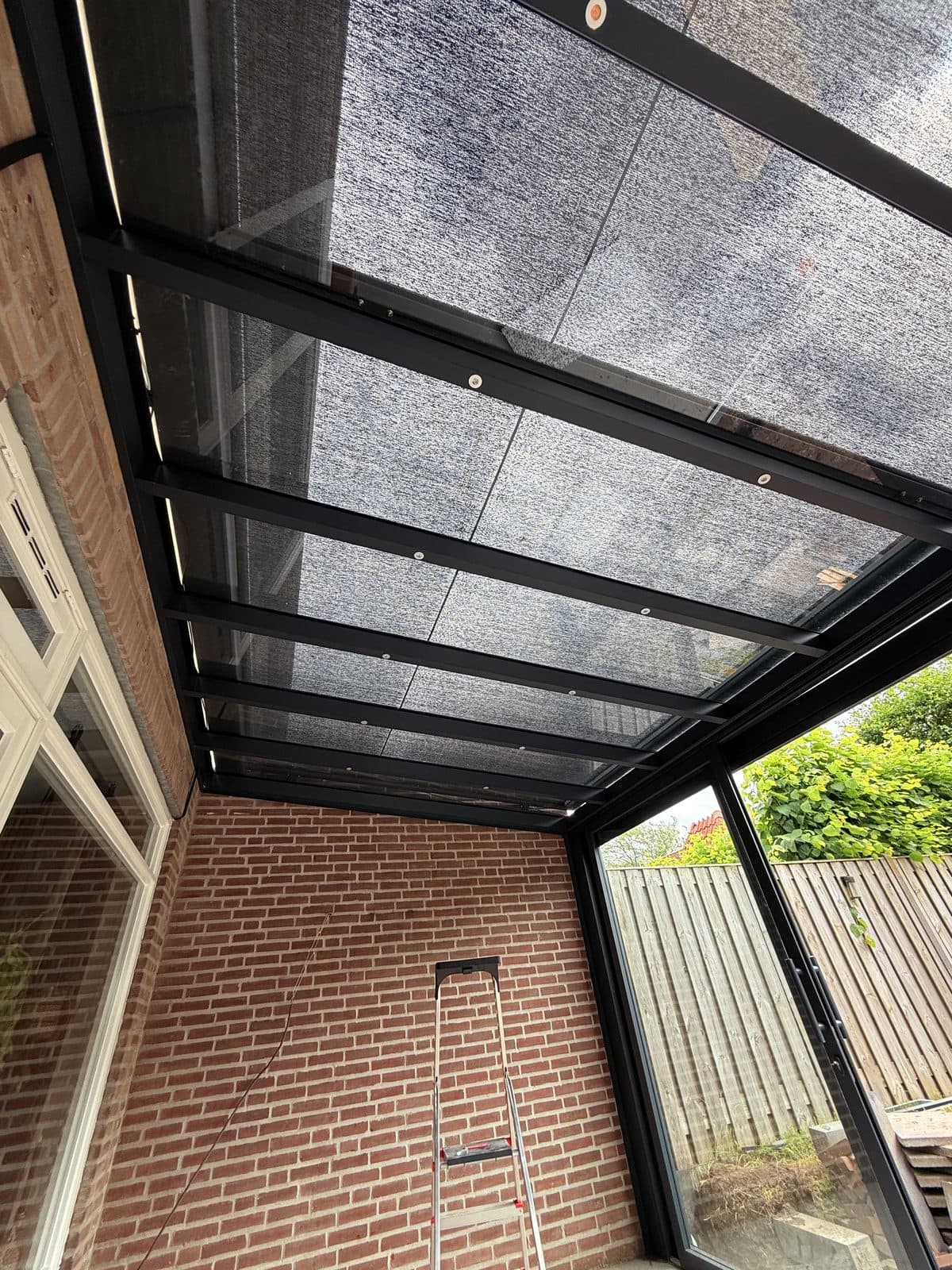 Glazen dak met zonwering en ledspots, gezien vanuit de overkapping